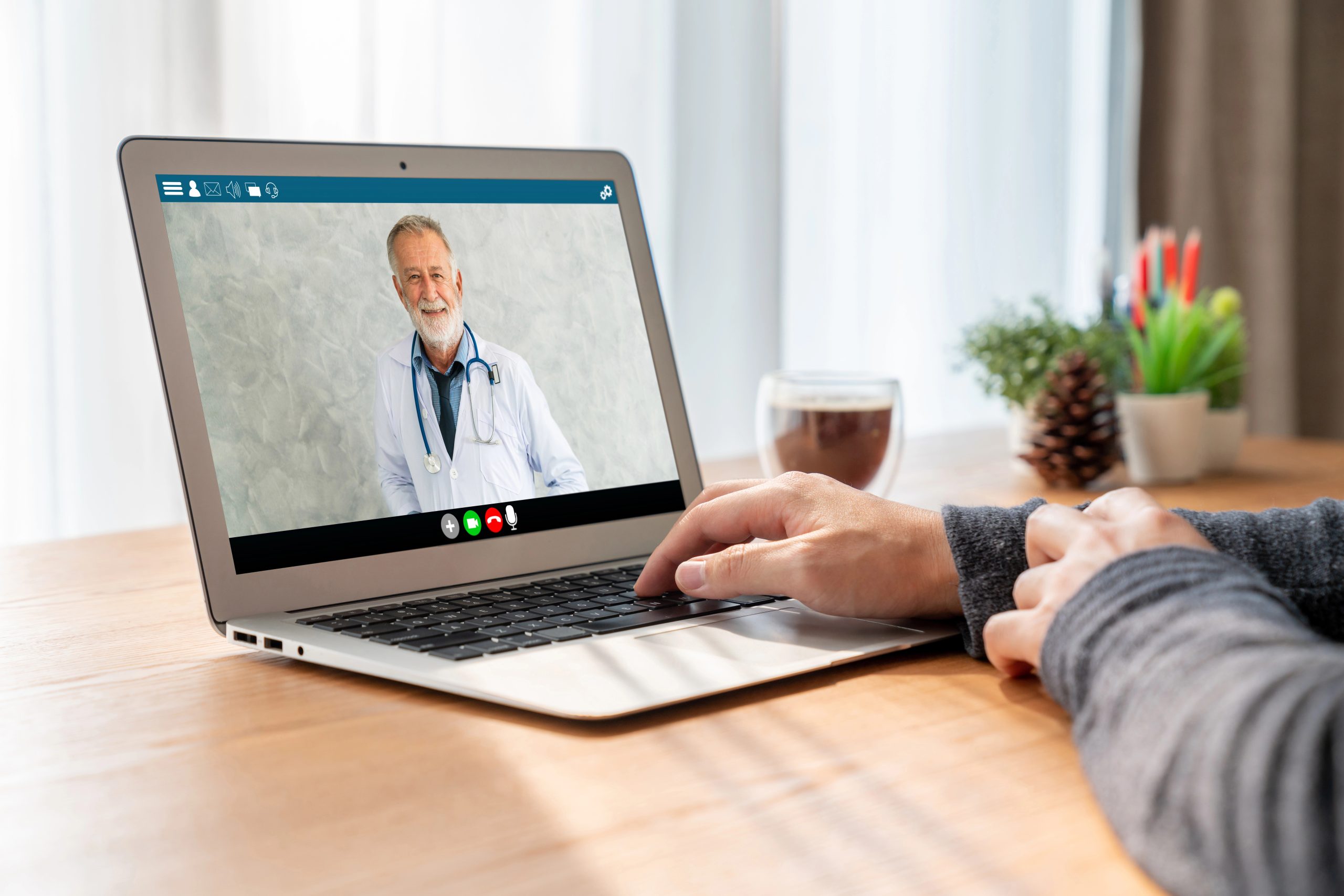 Person having a telehealth consultation with a hearing specialist on a laptop, discussing hearing care from the comfort of home.